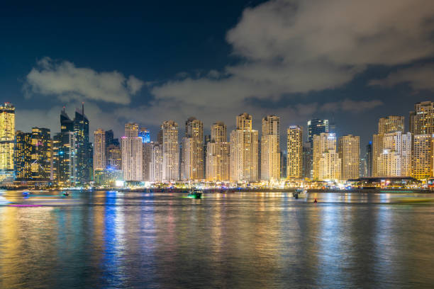 Skyscrapers in Ajman Free Zone illuminated at night, reflecting on the waters, highlighting business potential.