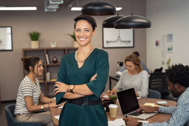 Office workers engaged in collaborative tasks, with a smiling woman standing confidently in the foreground.