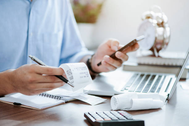 Person categorizing business expenses with receipts, laptop, and calculator on a desk.