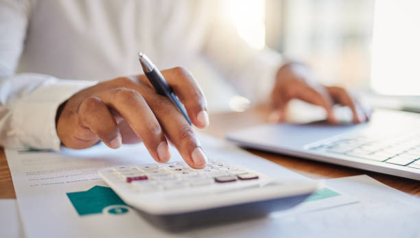 A person using a calculator and laptop to categorize business expenses.